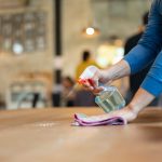 Waiter cleaning the table with spray disinfectant on table in restaurant